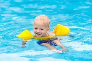 a toddler in pool wearing armbands