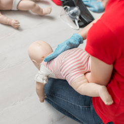 lady performing back slaps on choking baby manakin