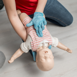 lady performs chest compressions on choking baby manakin
