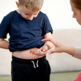 Adult injecting child with diabetes in stomach